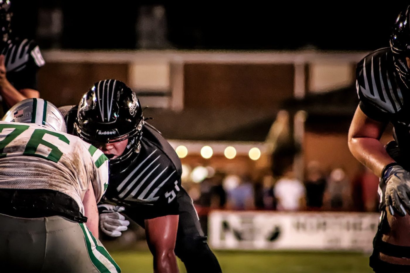 Panther linemen firing off the ball at the snap under stadium lights